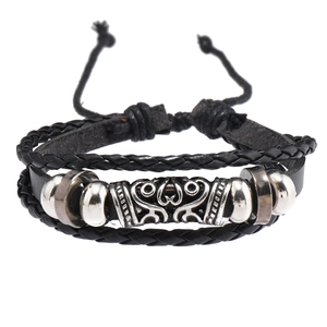 Détail d'un bracelet multicouche en cuir tressé noir avec perles et ornements en métal