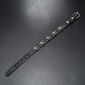 Detail of black punk leather bracelet with five silver skull charms and buckle strap