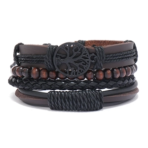 Macro shot of multi-layer leather bracelet set with metallic tree of life and wooden beads