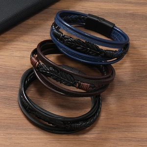 Détail de bracelets multicouches en cuir avec plume noire mate et fermoir magnétique