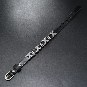 Détail d'un bracelet en cuir noir réglable avec cinq clous en métal argenté en forme de X