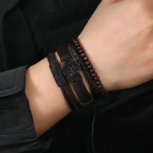 Detail of multi-layer leather bracelet set with tree of life charm on male wrist