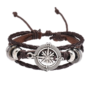 Détail d'un bracelet multicouche en cuir marron avec boussole argentée et perles métal