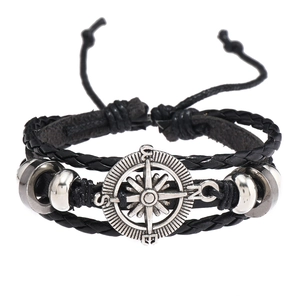 Détail du bracelet multicouche en cuir avec breloque boussole rétro et cordon ajustable