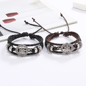 Détail de bracelets en cuir tressé à la main avec breloques boussole en alliage argenté