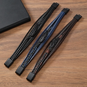 Gros plan de bracelets en cuir tressé multicouches avec breloques plumes sur bois