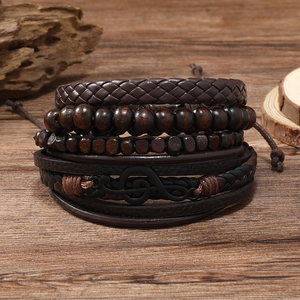 Detailed close-up of vintage multi-layer leather bracelets with musical G-clef on wood