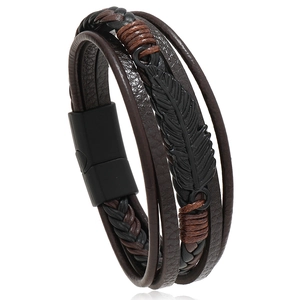 Détail du bracelet en cuir multicouche avec plume noire et fermoir magnétique