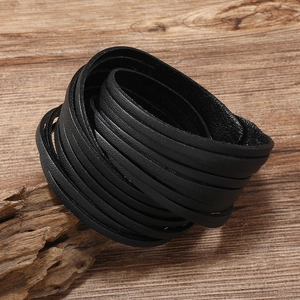 Men's dark multilayer leather tassel bracelet on a rustic natural wood background