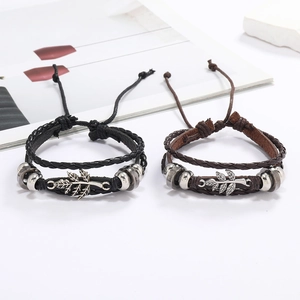 Détail de bracelets en cuir tressé vintage avec breloque feuille argentée et perles