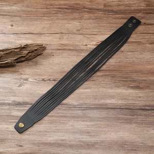 Men's black multilayer leather cuff bracelet with bronze snap buttons on wood background