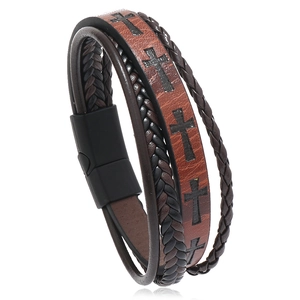 Close-up of layered leather bracelet featuring cross motif and black magnetic clasp
