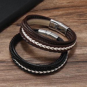 Detail of multi-layer woven leather bracelets with silver magnetic clasps on wood