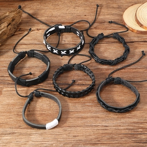 Set of 6 dark braided leather bracelets for men displayed on a rustic wood background