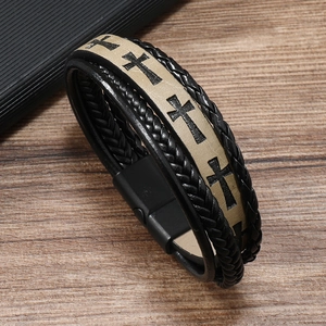 Close-up of men's leather bracelet featuring embossed cross patterns and magnetic buckle