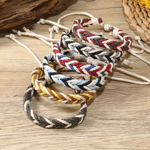 Detail of multi-colored braided cotton bracelets on a rustic wooden background