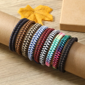 Handmade braided rope bracelets in various colors displayed on a wooden surface with decor
