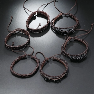 Detail van zesdelige herenarmbanden van bruin gevlochten leer met schedel- en kraalaccenten