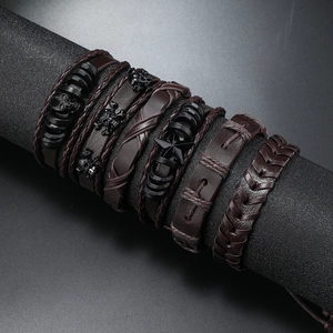 Detail van meerlaagse gevlochten lederen armbanden met schedel en ster metalen
