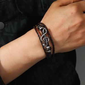Multi-layer brown leather bracelet with vintage silver treble clef musical note on a wrist