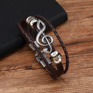 Macro shot of brown multi-layer braided leather bracelet with vintage silver music note charm