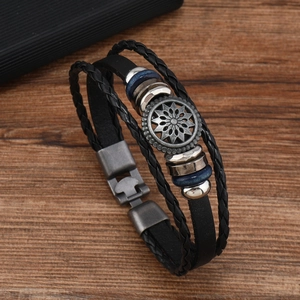 Details eines Vintage-Lederarmbands mit mehrschichtigem Geflecht und Sonnenblumen-Metallanhänger