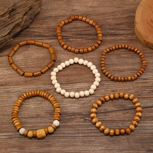 Set of six vintage warm-tone wooden bead bracelets for men on a dark wood floor