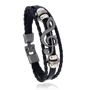 Close-up of multilayer leather bracelet featuring a silver treble clef music note charm