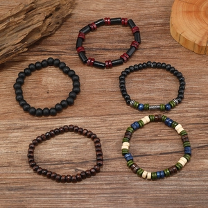 Five assorted vintage wooden and matte black beads bracelets on a rustic wood background