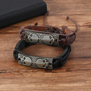 Bracelets homme en cuir avec plaque métal crâne rétro sur fond bois style vintage