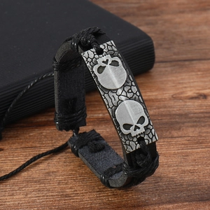 Détail de la plaque tête de mort vintage sur bracelet en cuir tressé noir pour homme