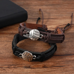 Two-piece volleyball charm braided leather bracelets in black and brown on wood