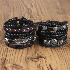 Detail of vintage layered leather bracelets with wood beads, feathers and metal charms