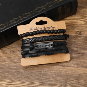 Dettaglio del set di quattro bracciali neri da uomo in pelle e perline con targa metallica