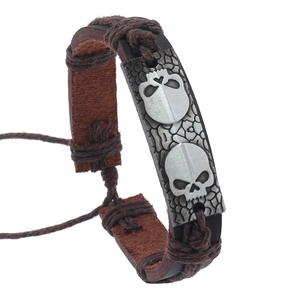 Détail d'un bracelet punk en cuir tressé avec plaque en alliage et motifs de crânes