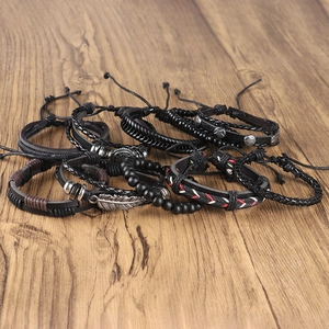 Detail of multi-layer leather bracelets set with metal feather and star charms on wood