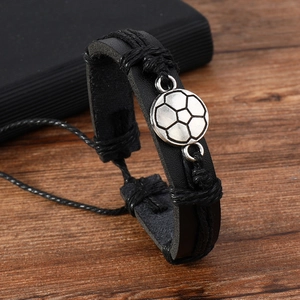 Close-up of a braided leather soccer bracelet with a silver football charm on wood