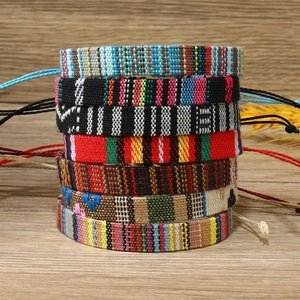 Close-up of bohemian woven friendship bracelets in colorful patterns on wood background