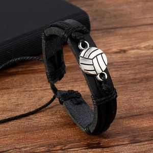 Detail of a black woven leather volleyball bracelet with a vintage silver metal charm