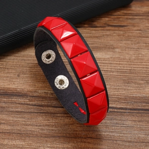 Détail d'un bracelet punk en cuir rouge avec clous pyramides assortis et fermoir à pression