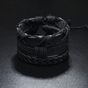 Macro detail of layered black men's leather bracelet with woven tree of life texture