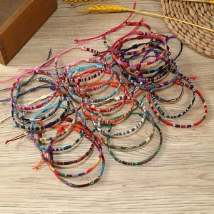 Bohemian woven couple bracelets in various colors displayed on a rustic wooden surface