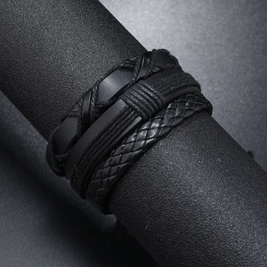 Macro detail of men's multi-layer leather bracelet with intricate braided cords and texture