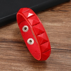 Détail d'un bracelet punk en cuir rouge avec rivets carrés et fermoirs à pression