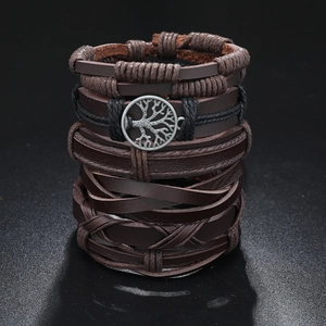 Close-up of multilayer leather bracelets with a Tree of Life metal charm on dark surface