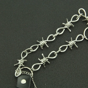 Détail d'une chaîne en métal argenté style punk avec pendentif en cuir noir attaché
