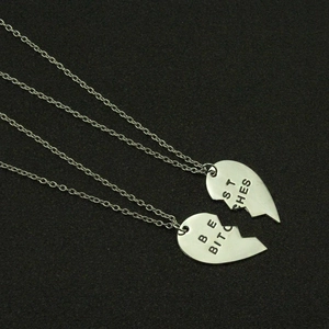 Two-piece silver heart pendant necklace set with Best Bitches engraving on grey background