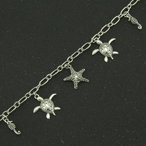 Silver ocean charm bracelet with sea turtle and starfish pendants on a black surface