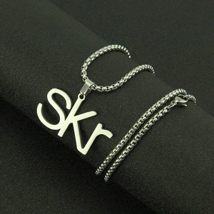 Polished stainless steel SKR letter pendant necklace with silver box chain on dark grey stand