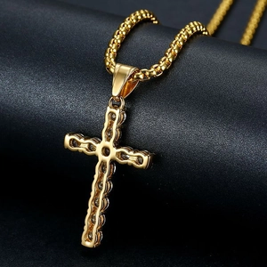 Macro shot of gold-plated cross pendant with cubic zirconia on black leather background